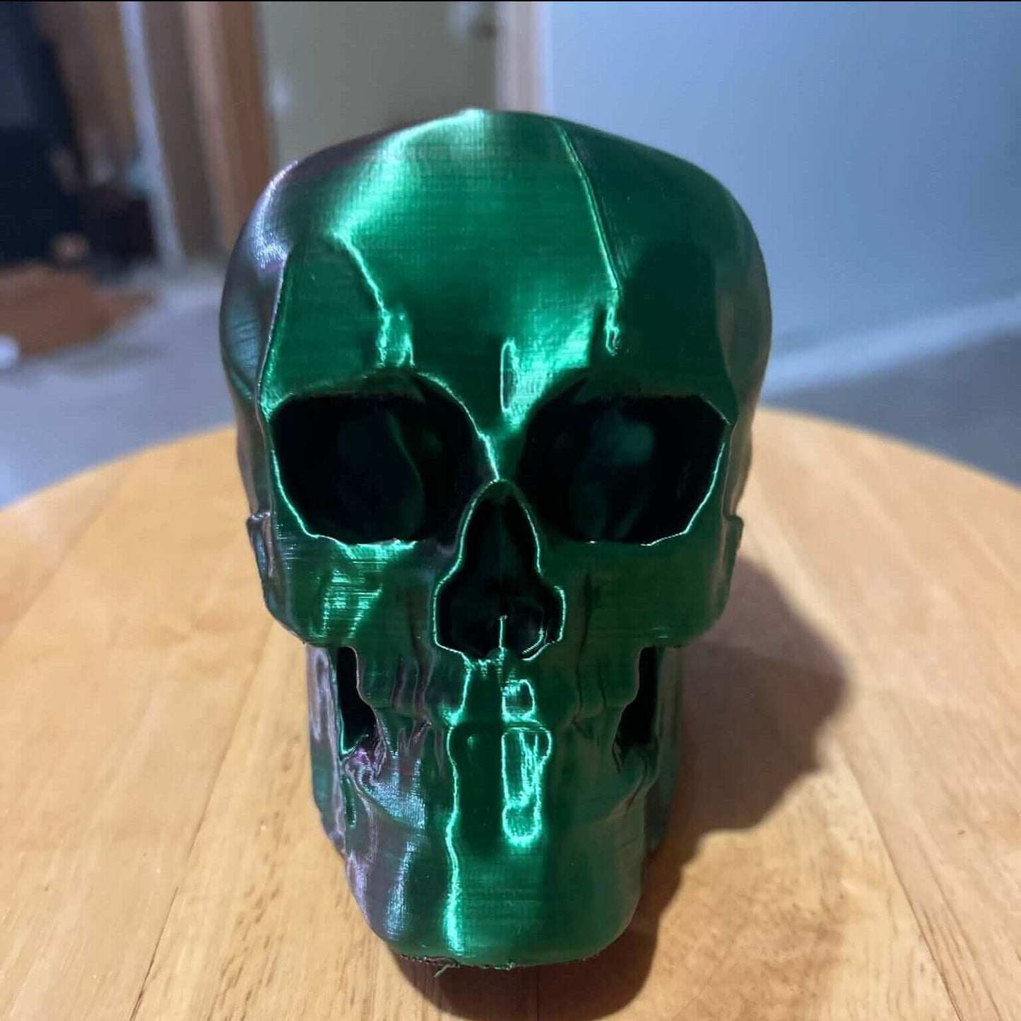 Shiny green 3D printed human skull replica on wooden night stand, realistic dual color gradient decor for desk, highlighting human anatomy